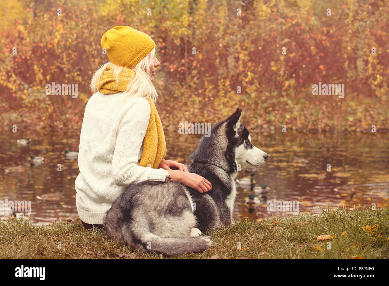 Romantic autumn portrait of a woman and her dog outdoors on the fall park background Stock Photo
