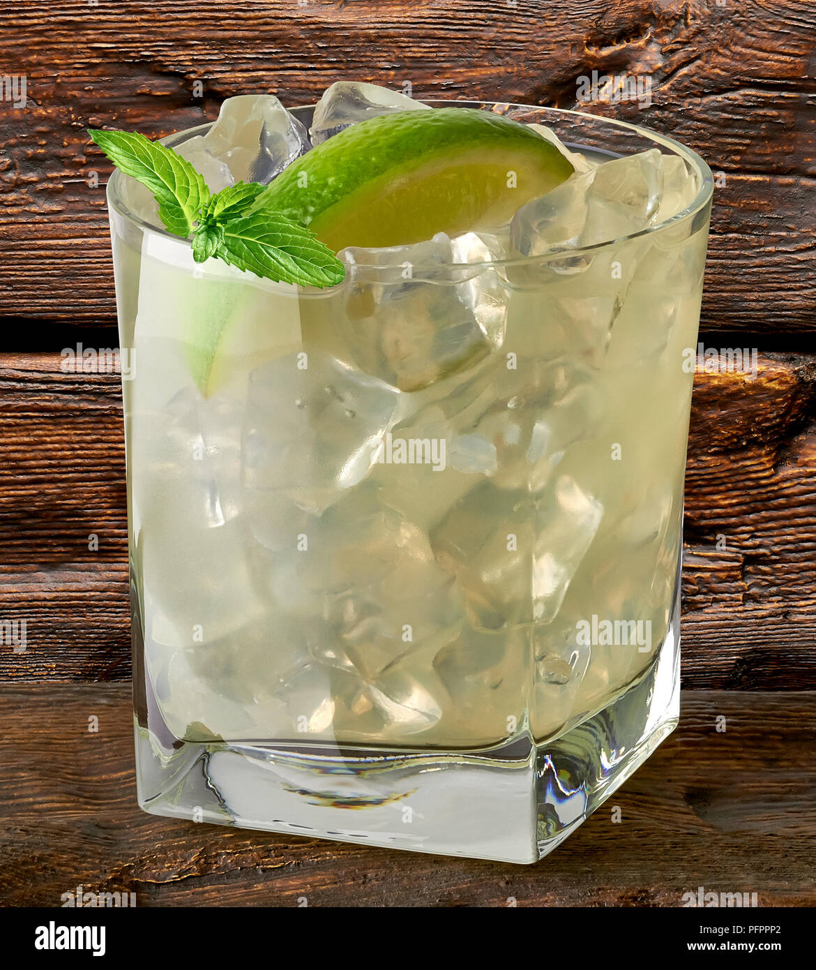 Vodka lime, gimlet, caipirinha or gin tonic with ice in glass on wooden background Stock Photo
