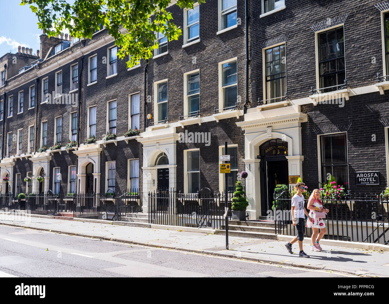 Couple walking in Gower Street in front of classic Georgian style townhouses in a summer sunny day. Fitzrovia, London, UK Stock Photo