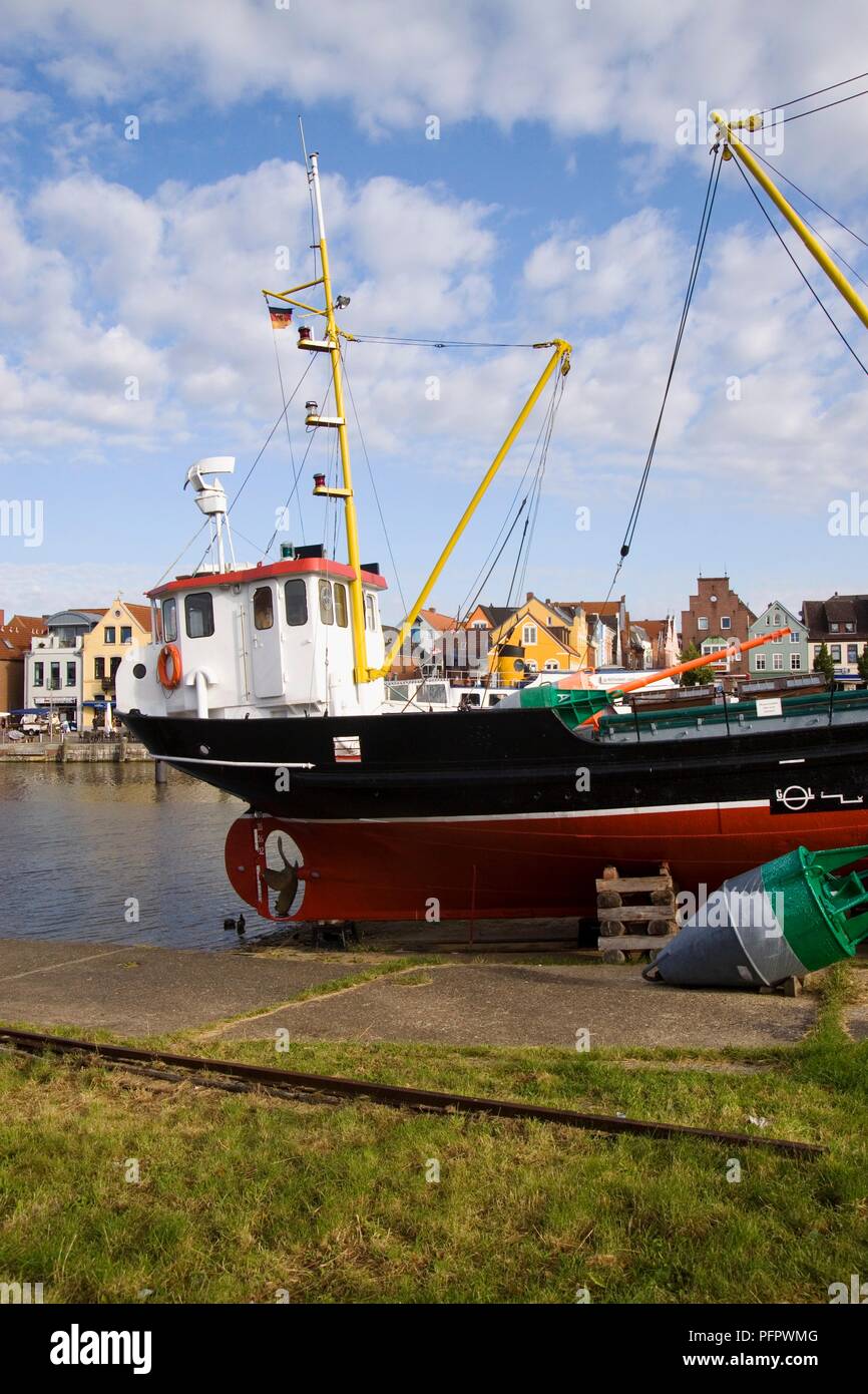 Germany, Schleswig-Holstein state, Husum town, view of town and moored fishing boat at harbour Stock Photo