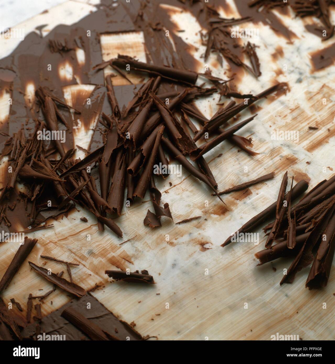 Chocolate shavings and melting chocolate on chopping board Stock Photo