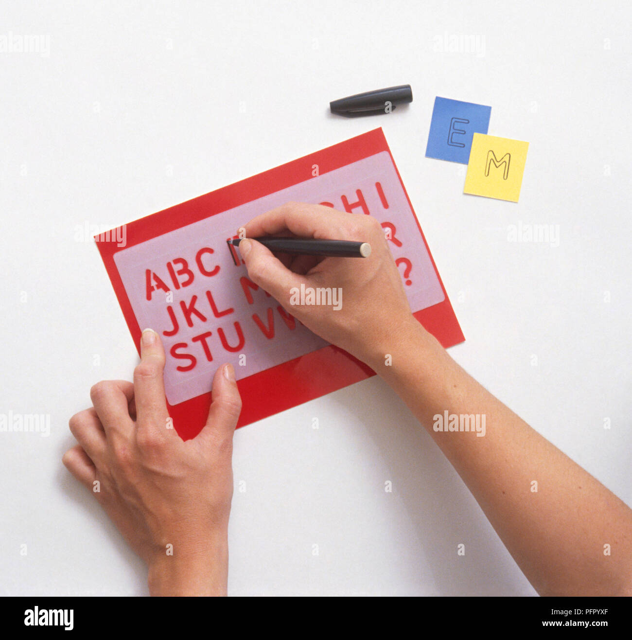 Woman's hands stencilling letters of the alphabet on paper, close-up ...