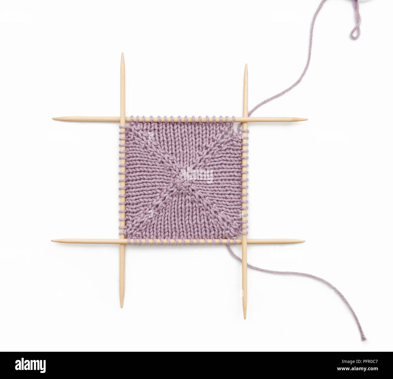 Purple knitted square inside four double-pointed needles Stock Photo