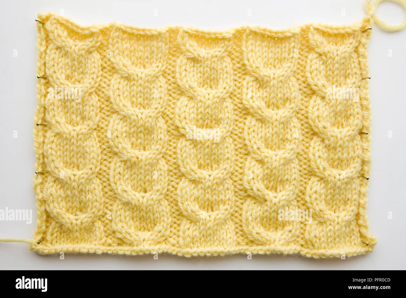 Piece of yellow knitting, showing horseshoe cable stitch Stock Photo