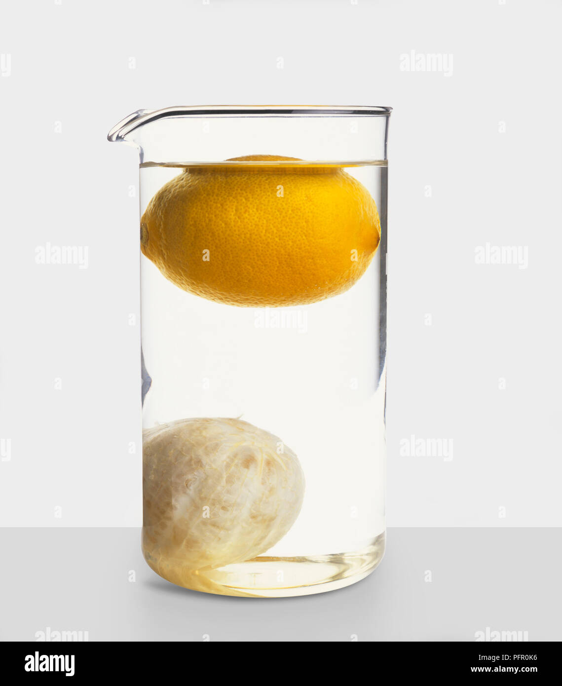 Peeled satsuma at bottom of jug of water with whole lemon floating above Stock Photo