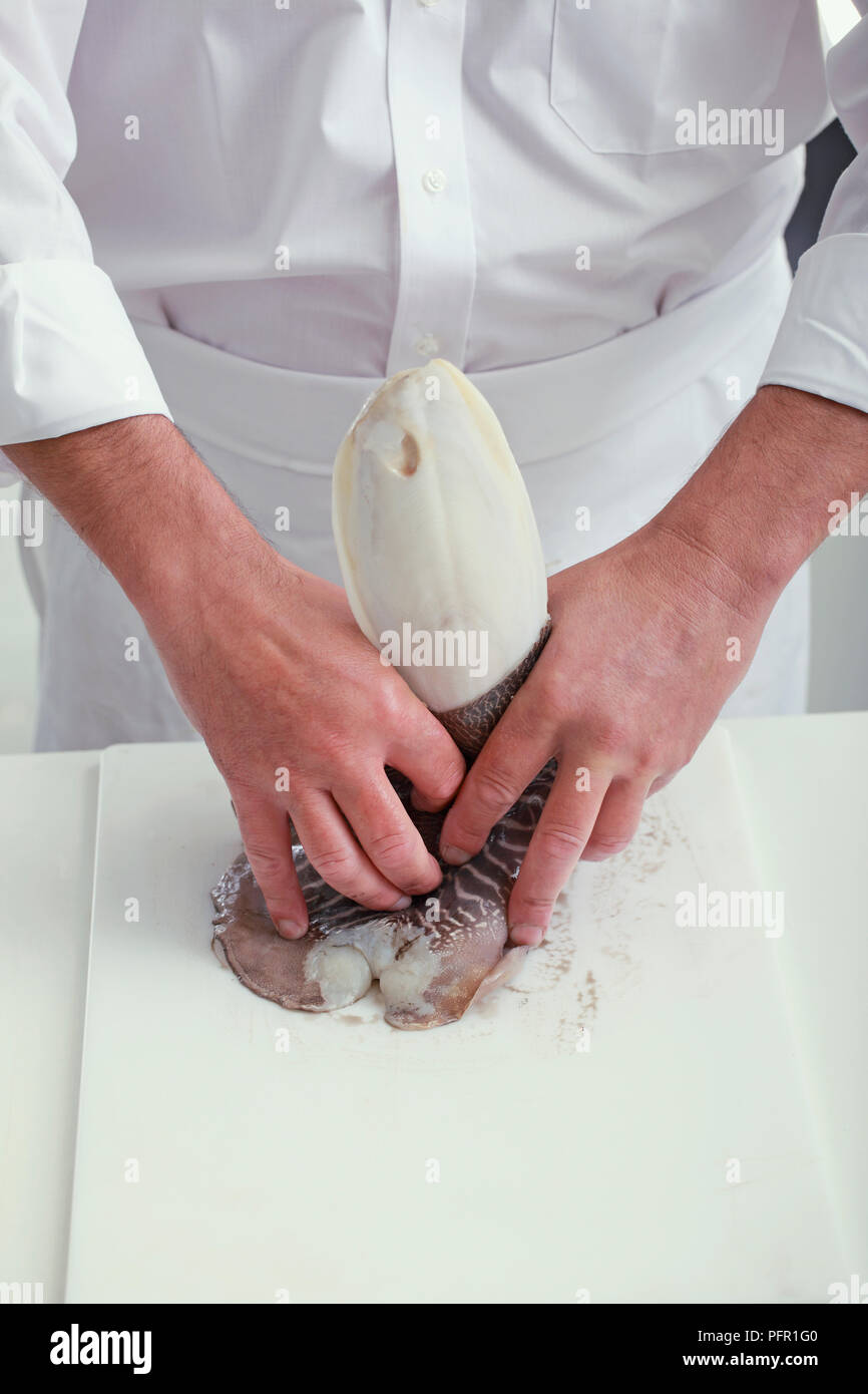 Removing bone of cuttlefish, pressing down to release internal shell and peeling back outer skin Stock Photo