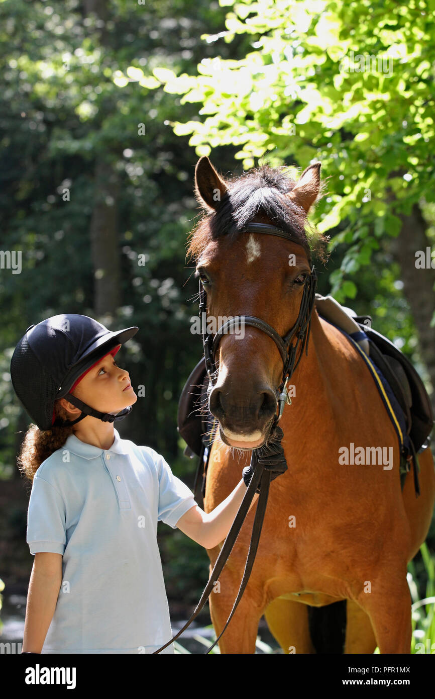 Girl holding horse by the reins Stock Photo
