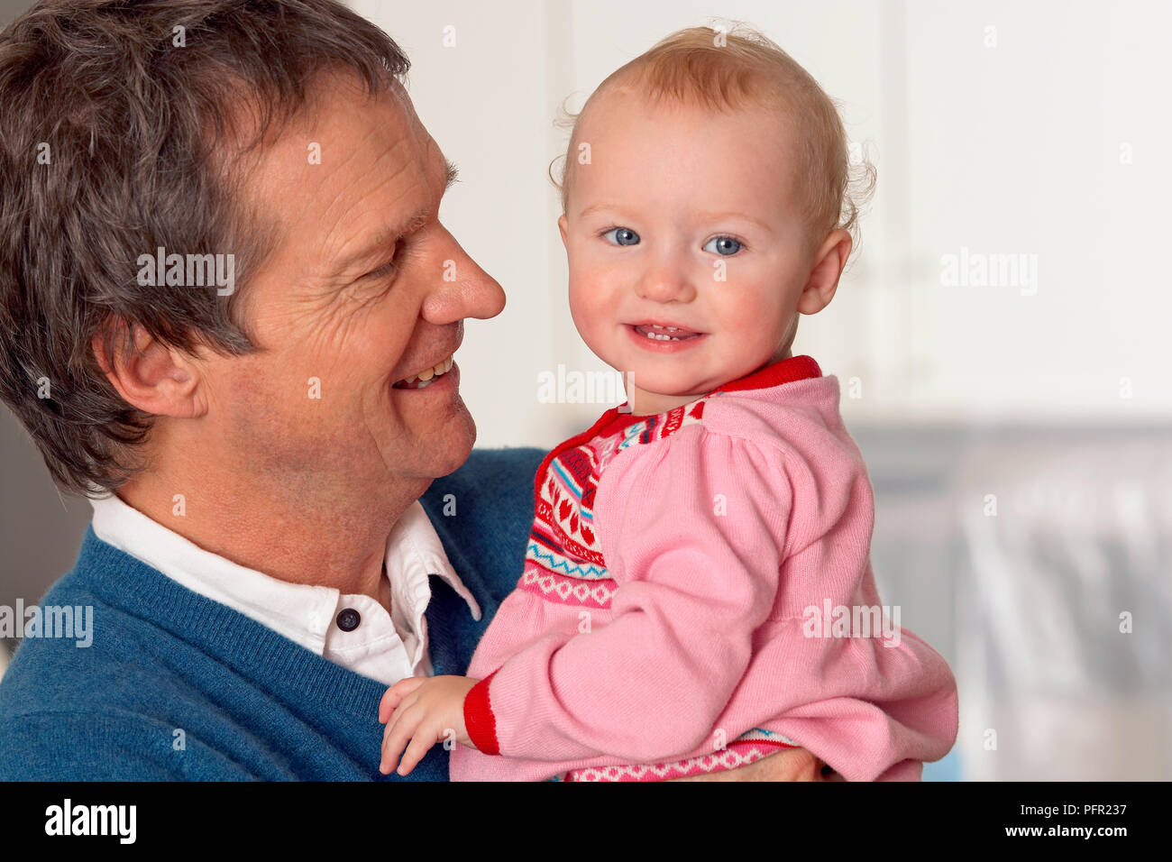 Grandfather in profile smiling and holding baby granddaughter in his ...