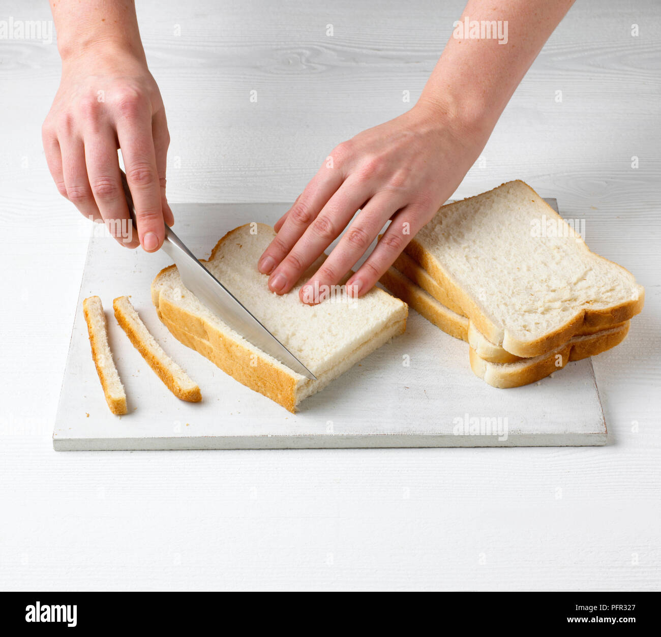 Cutting off the crusts from slices of white bread Stock Photo Alamy