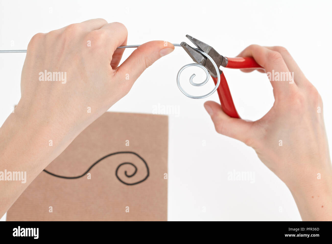Using pliers to bend piece of wire into spiral shape Stock Photo Alamy