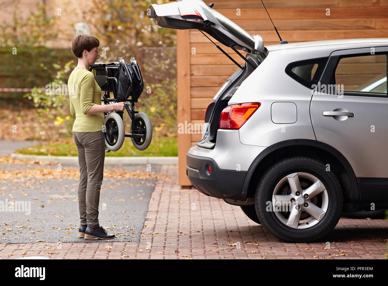 Woman folding up wheelchair to go in boot of car Stock Photo Alamy