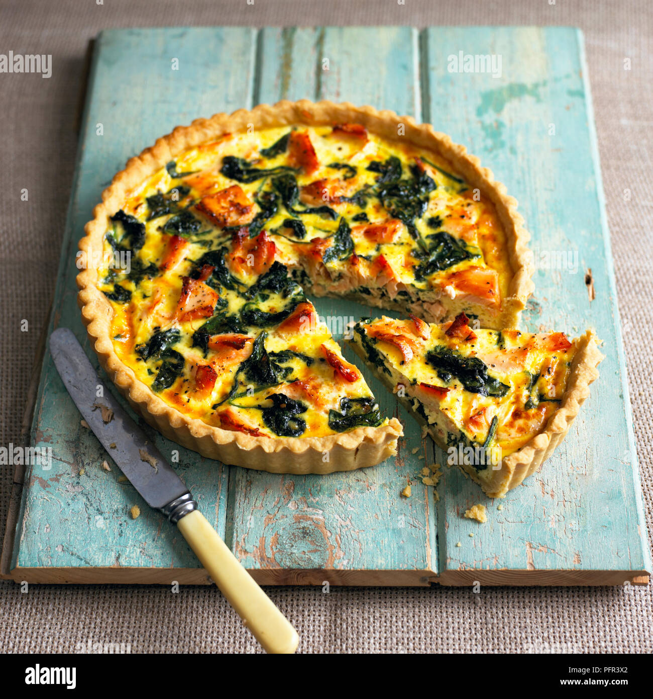 Salmon and spinach quiche with single slice cut away from the rest Stock Photo