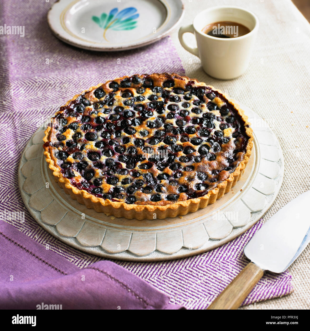 Blueberry cream cheese tart, cake server, coffee cup and plate nearby Stock Photo