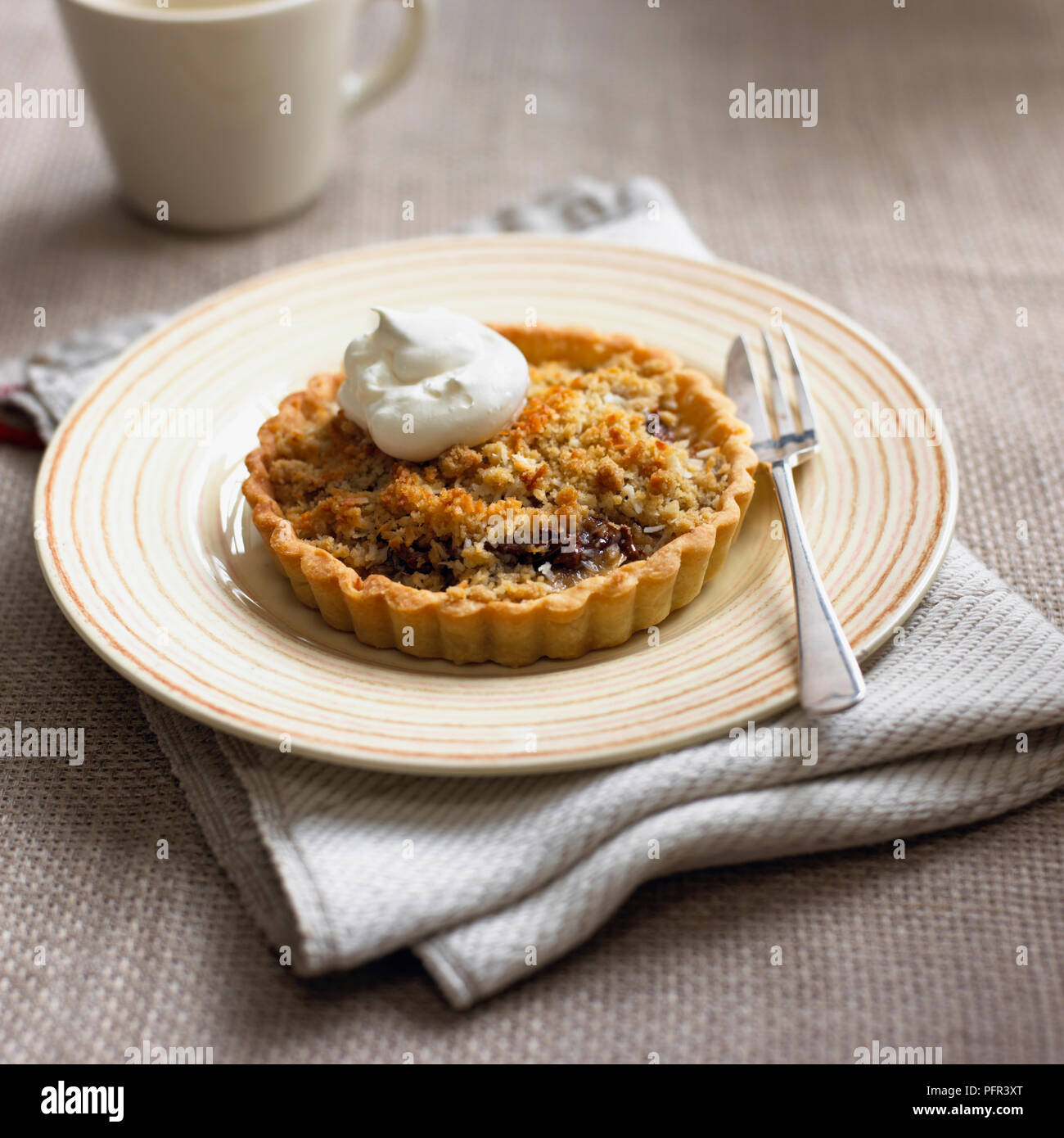 Banana and chocolate spread crumble tartlet, served with dollop of cream Stock Photo