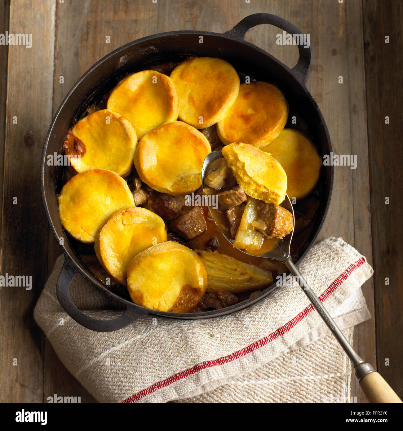 Beef, fennel and mushroom cobbler in cast-iron pan, with spoon Stock Photo