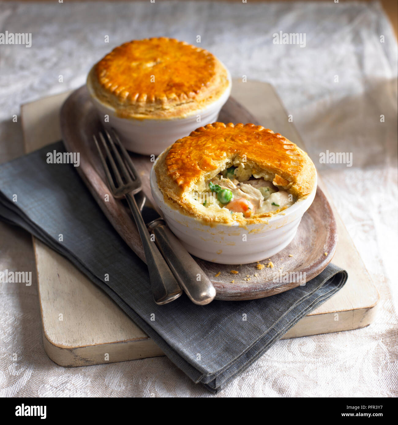 Two chicken pot pies on serving tray, with cutlery Stock Photo