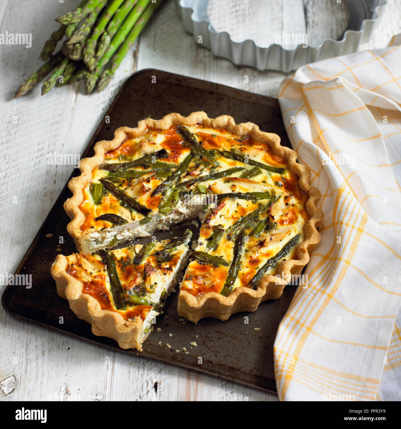 Chicken, asparagus and tarragon tart on baking tray, single slice cut away from the rest Stock