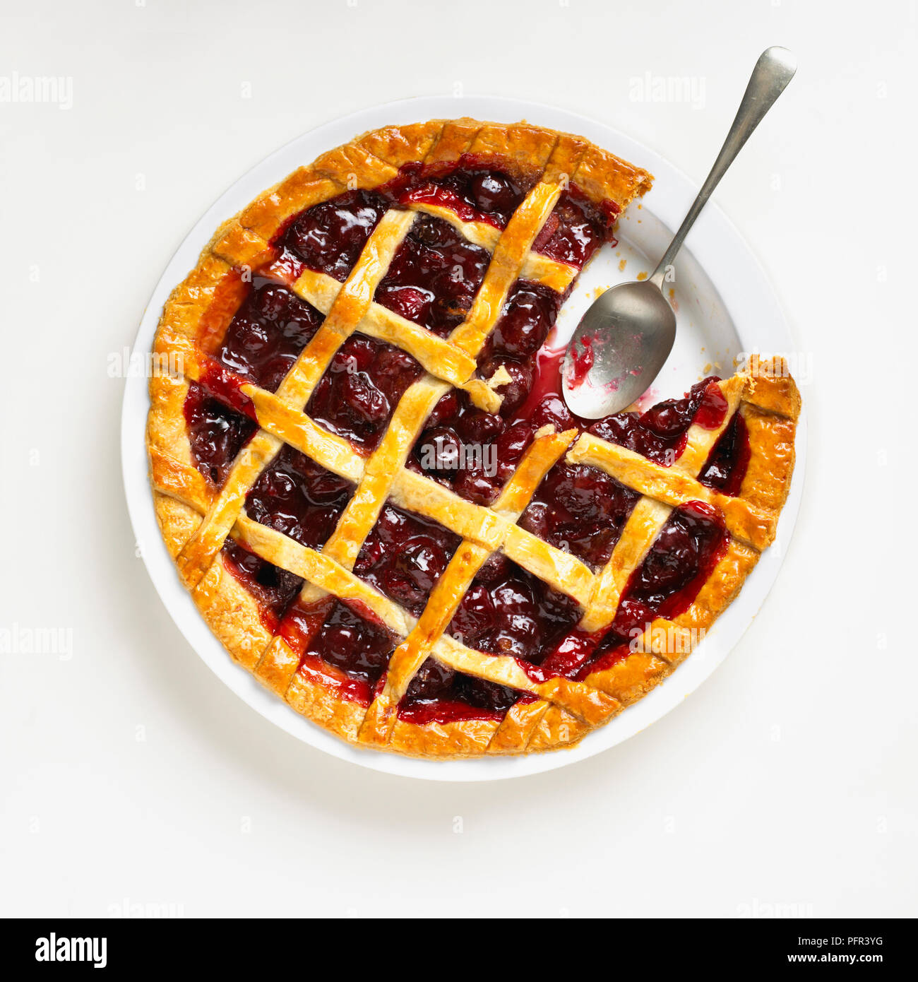 Cherry lattice pie with piece missing, and silver spoon Stock Photo