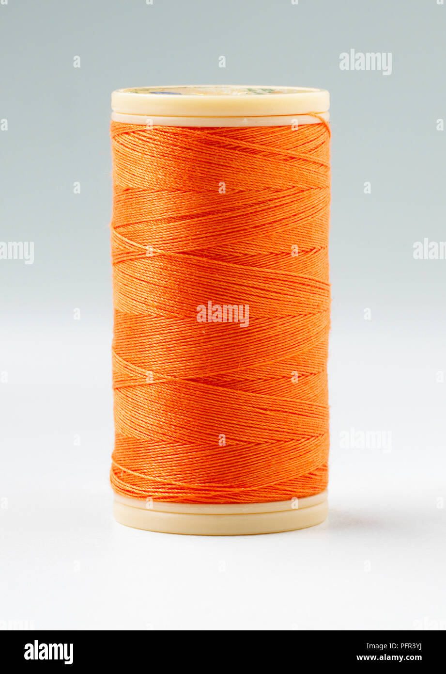 Reel of bright orange cotton sewing thread Stock Photo