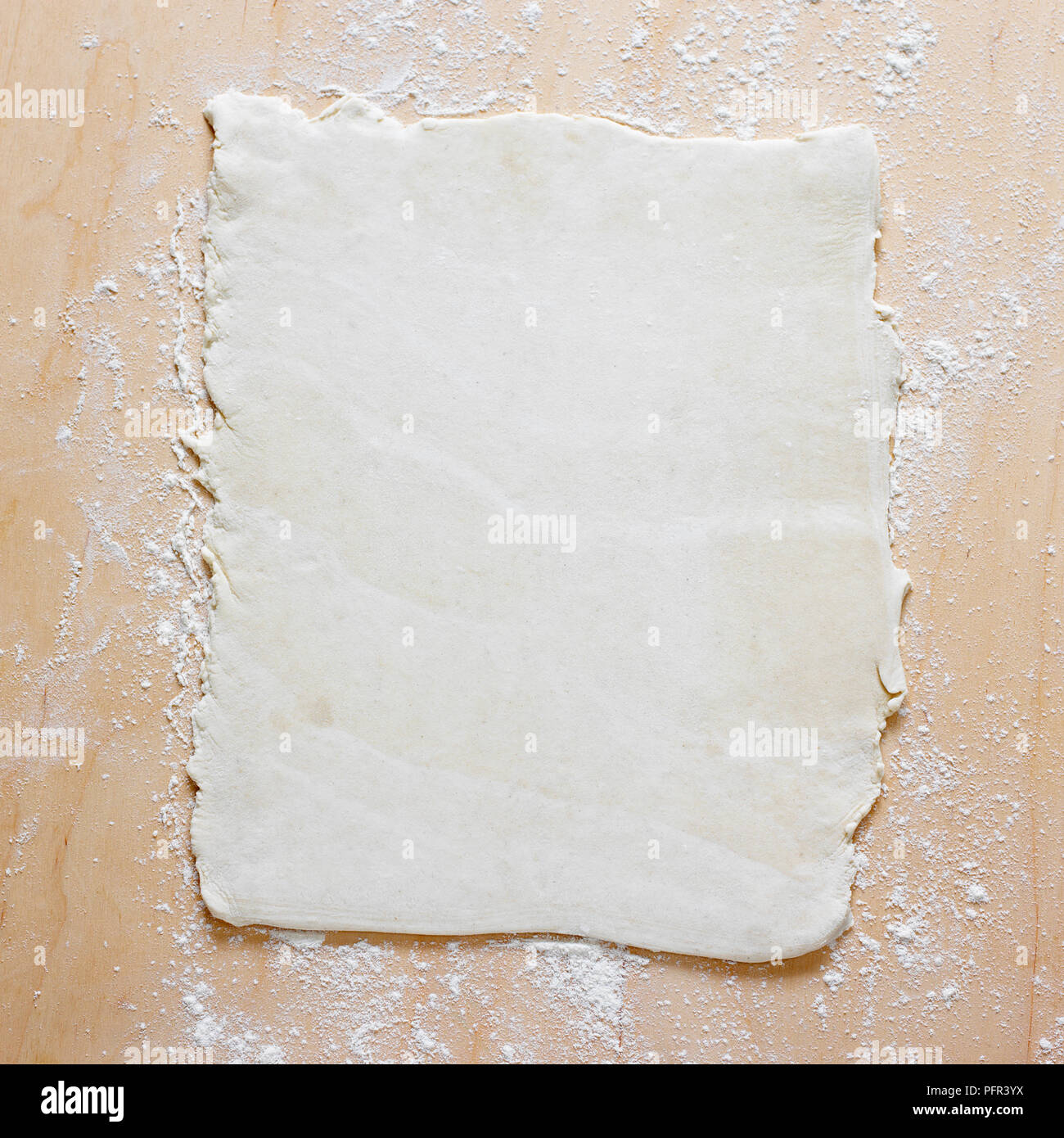 Pastry dough rolled out on floured surface Stock Photo