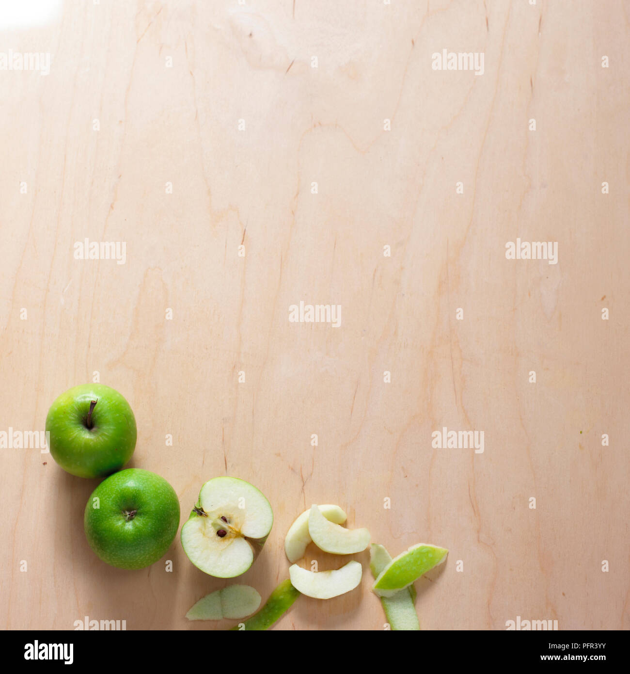 Whole apples and sliced and peeled segments on wooden surface Stock Photo