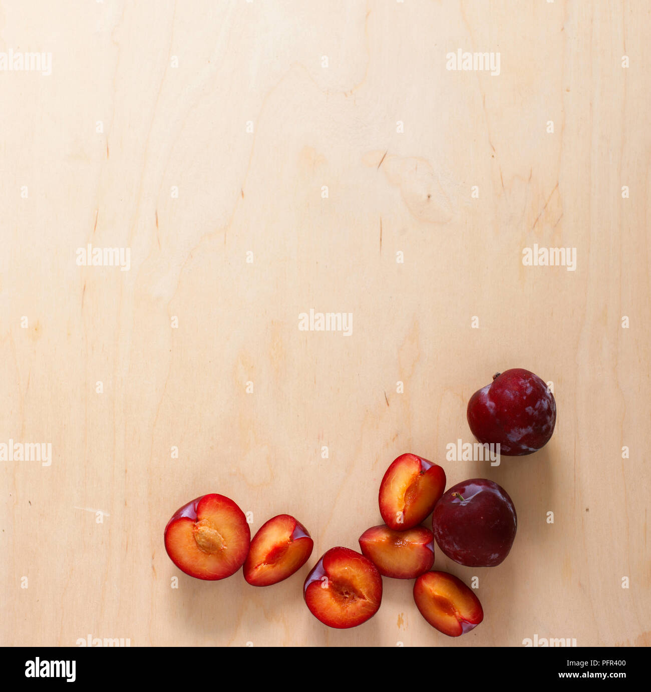 Whole, cored and sliced plums on wooden surface Stock Photo