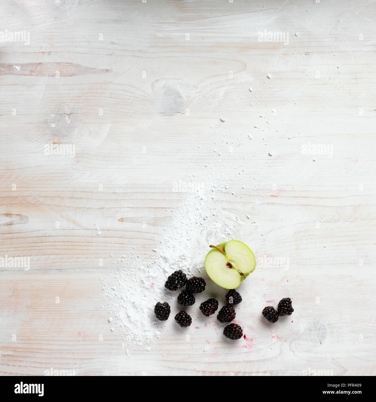 Half apple and blackberries on floured wooden surface Stock Photo