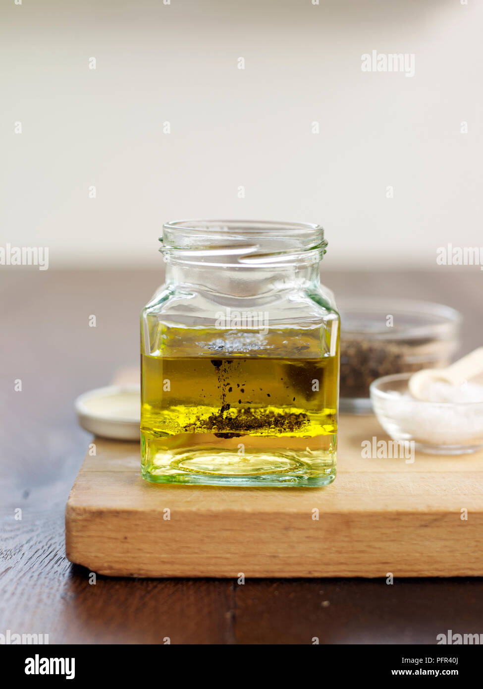 White wine vinegar, olive oil, and pepper in small jar (making vinaigrette) Stock Photo