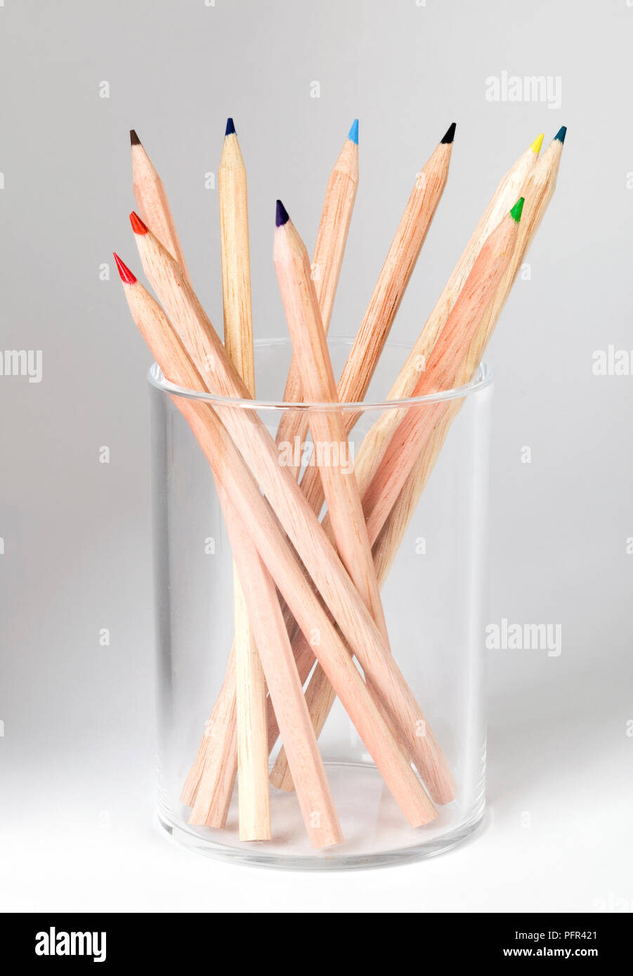 Coloured pencils in clear glass holder Stock Photo