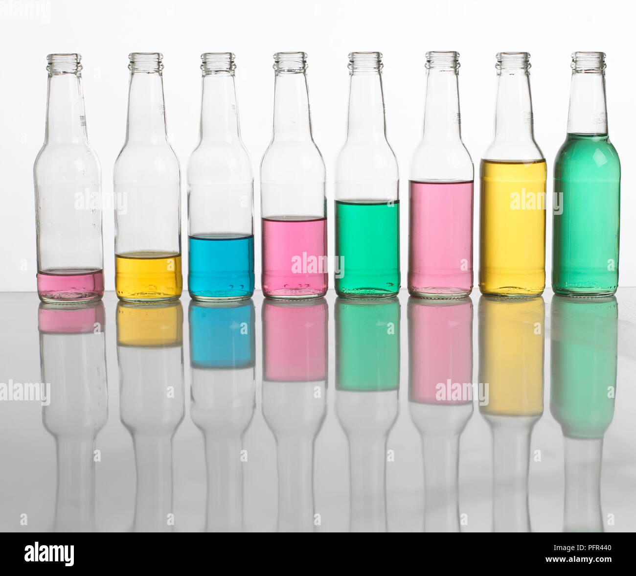 'Bottle pipes' or 'bottle xylophone', bottles filled with different amounts of coloured water, lined up in a row Stock Photo