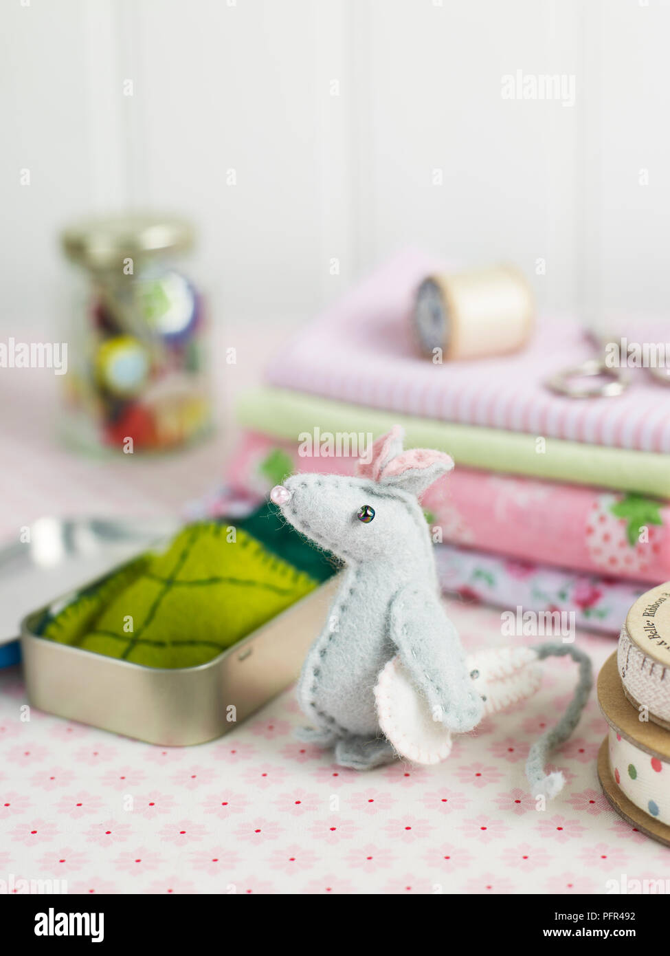 Felt mouse and tin surrounded by craft materials Stock Photo