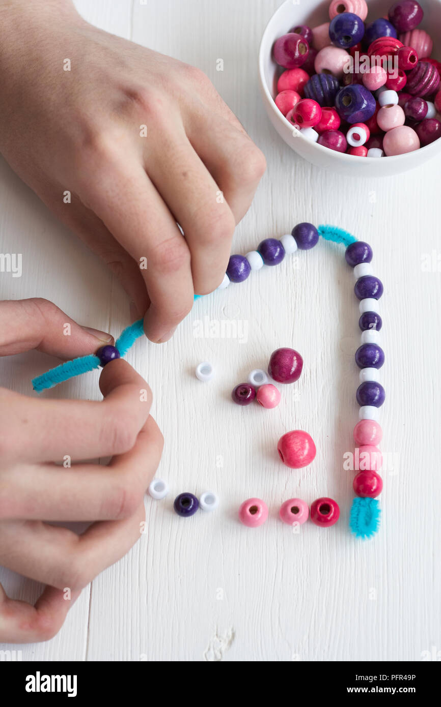 Threading beads on pipe cleaner Stock Photo