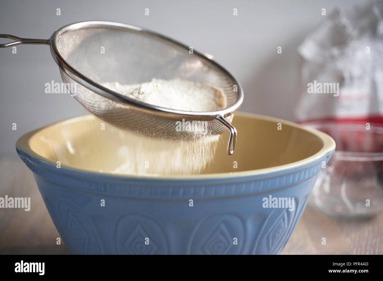 Sifting flour into mixing bowl Stock Photo