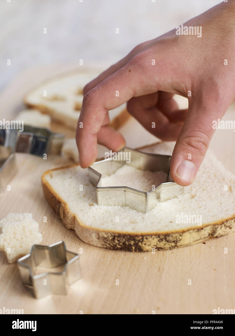 Using star-shaped cookie cutter on slice of white bread, to make croutons Stock Photo