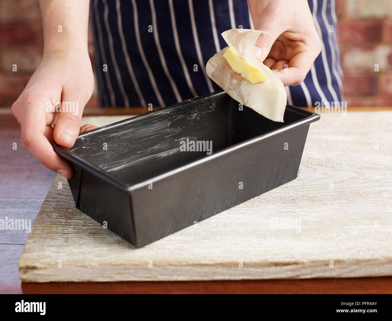 Making bread, buttering a loaf baking tin Stock Photo