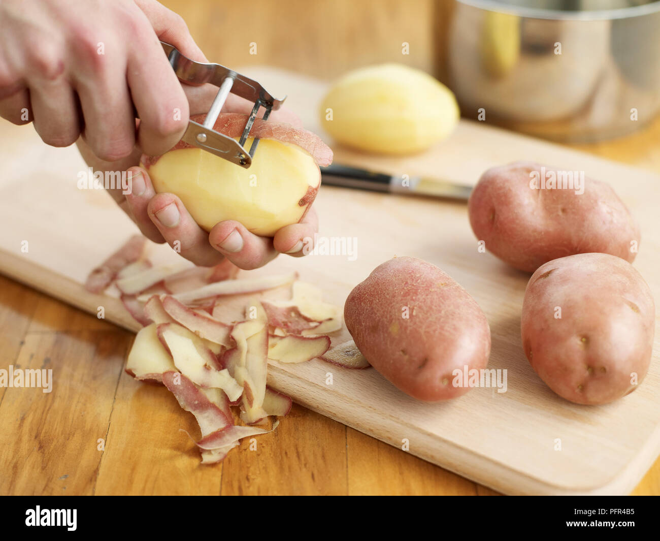 Peeling potatoes with potato peeler Stock Photo