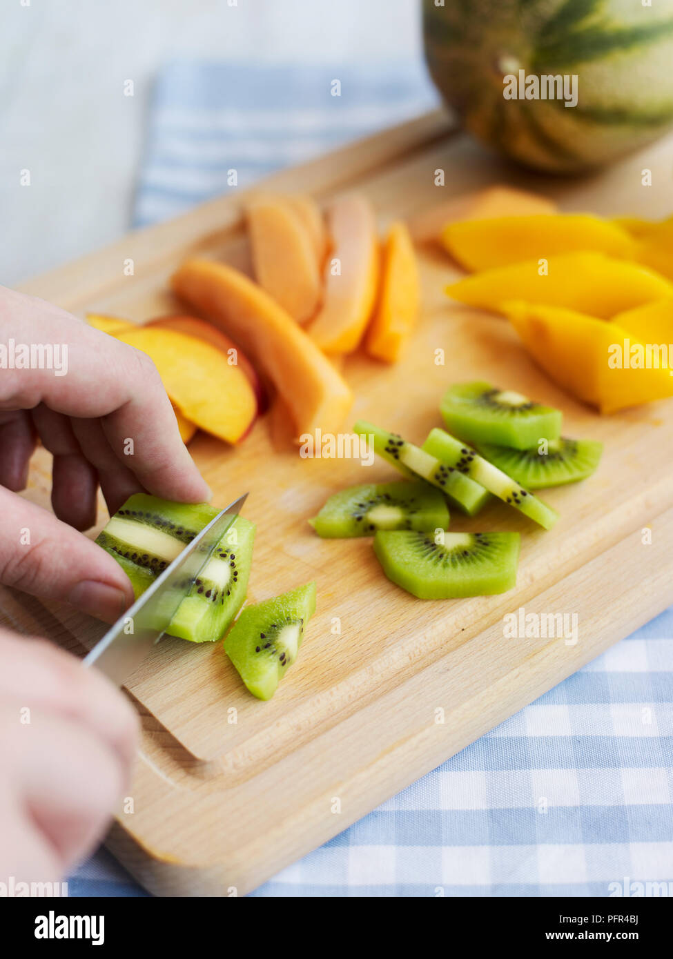 Chopping mangoes and kiwis Stock Photo