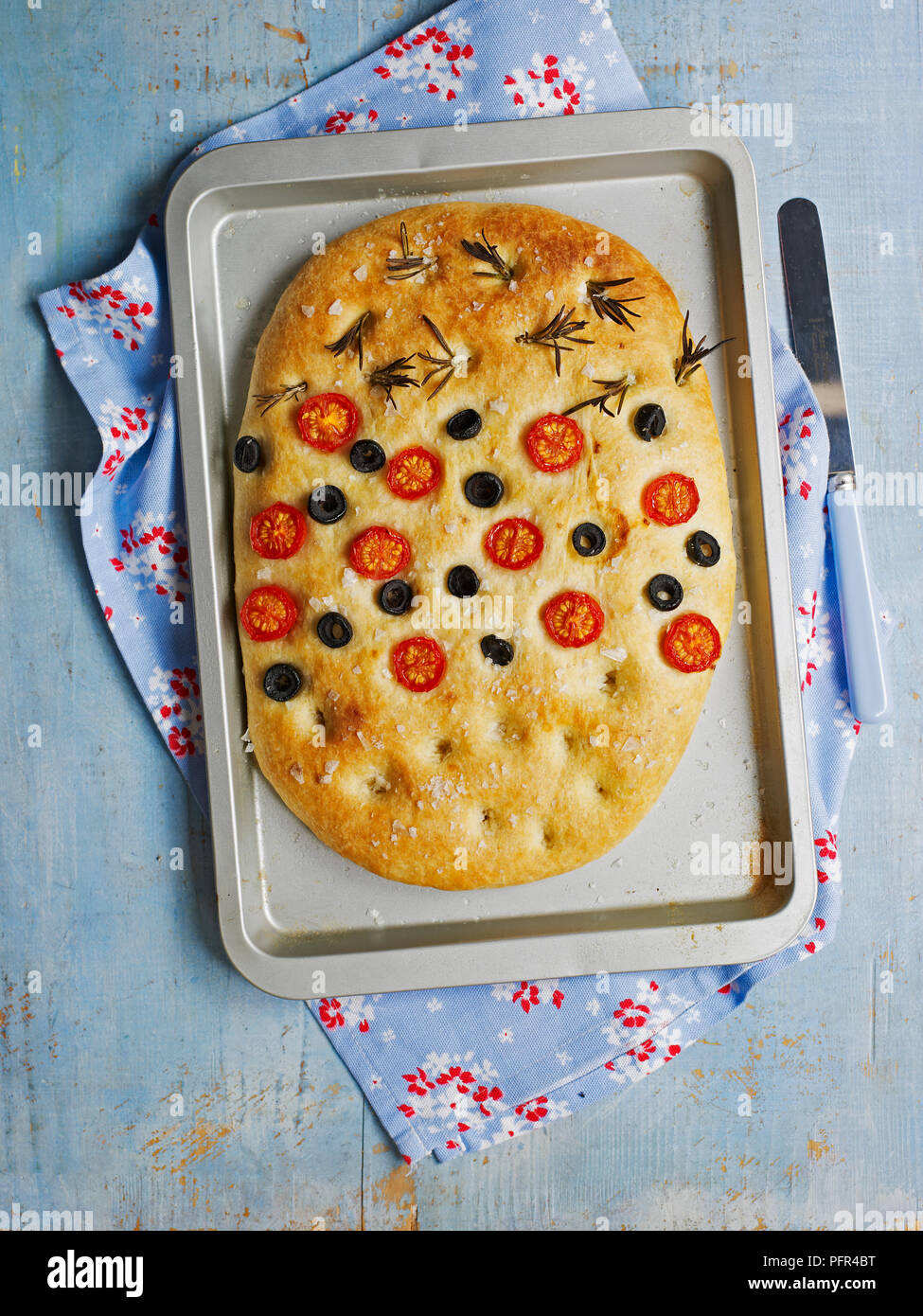 Focaccia bread studded with rosemary, tomatoes, and olives Stock Photo