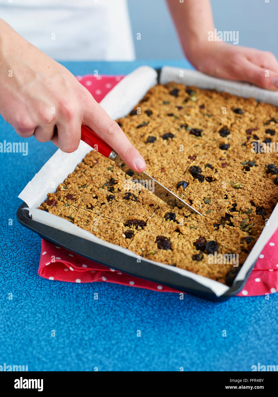 Cutting baked muesli bars (cereal and fruit bars) into slices Stock Photo