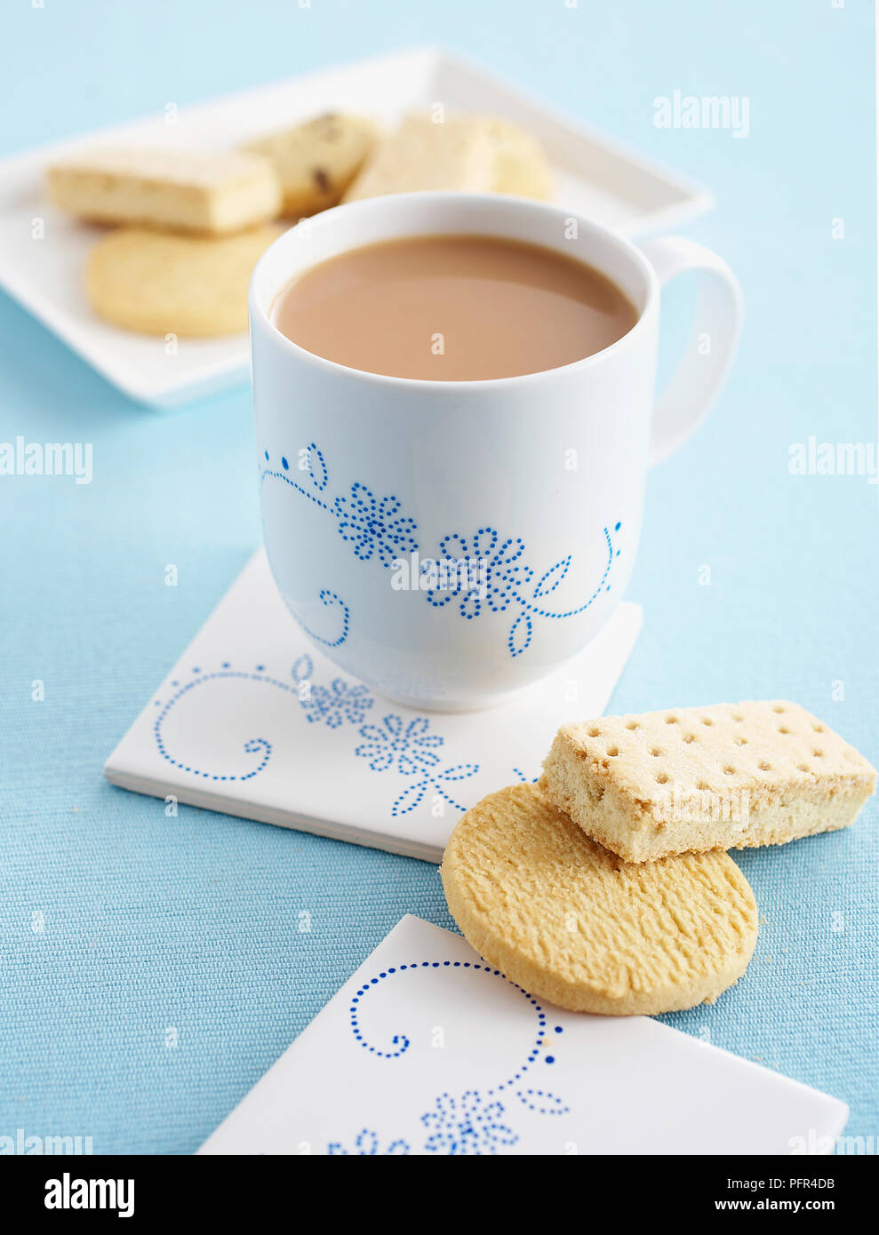 Cup of milky tea, butter biscuits and shortbread, Dot decorated cup and coaster Stock Photo