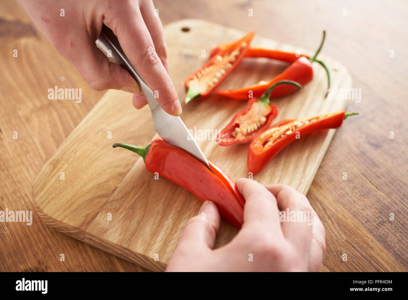 Slicing red chillies in half Stock Photo