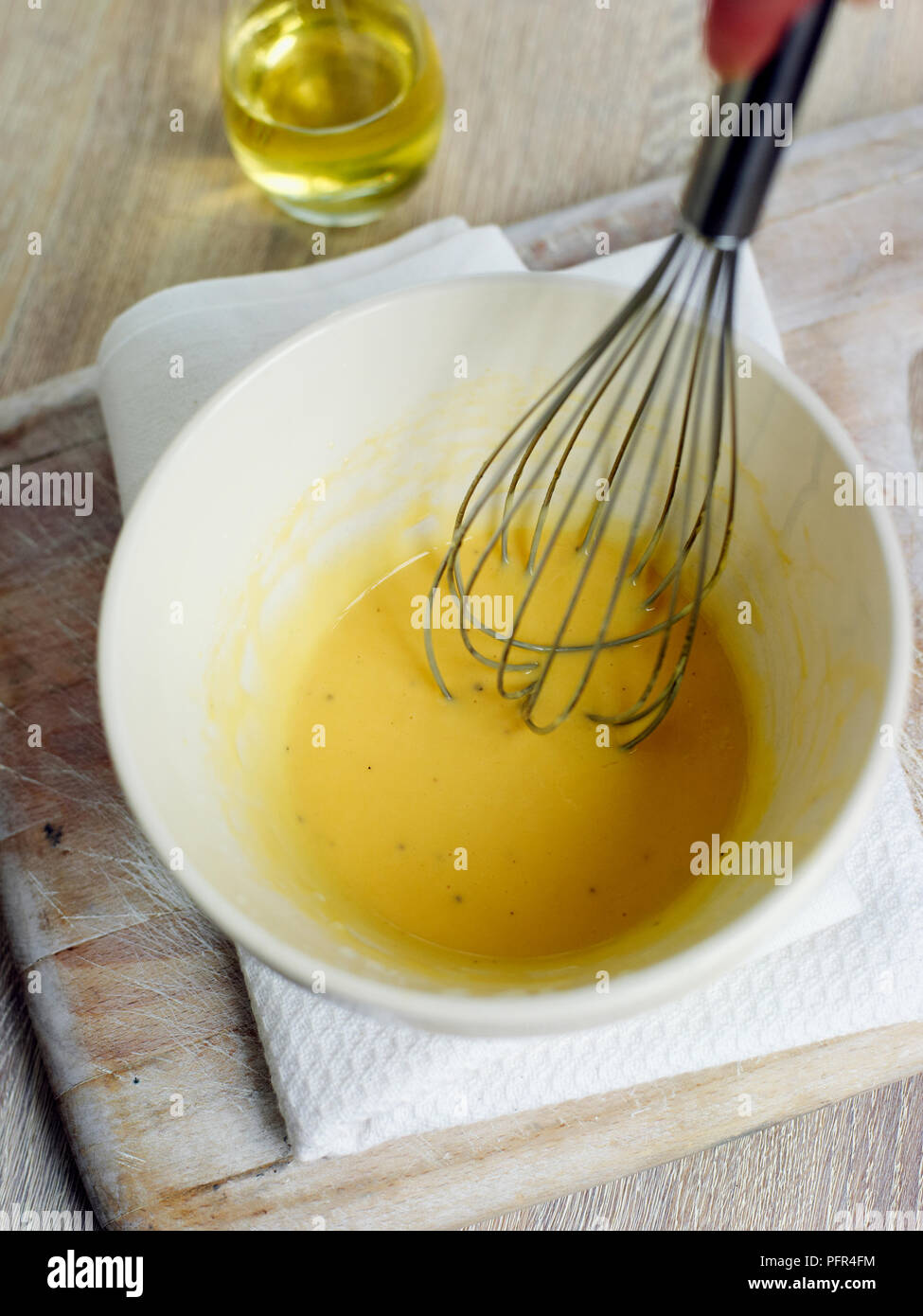 Mixing together olive oil, eggs and mustard (making mayonnaise sauce