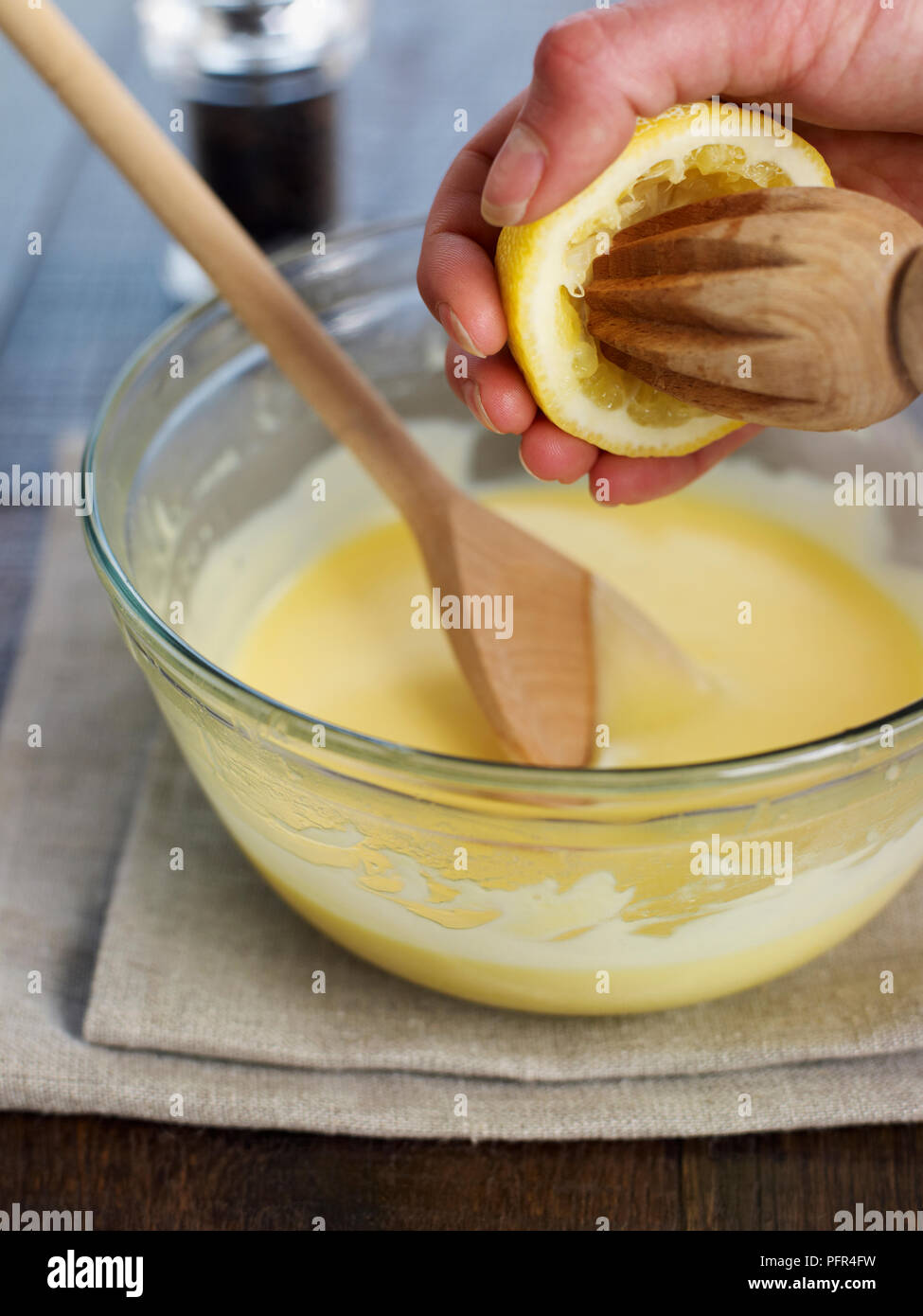 Adding freshly squeezed lemon juice to hollandaise sauce Stock Photo