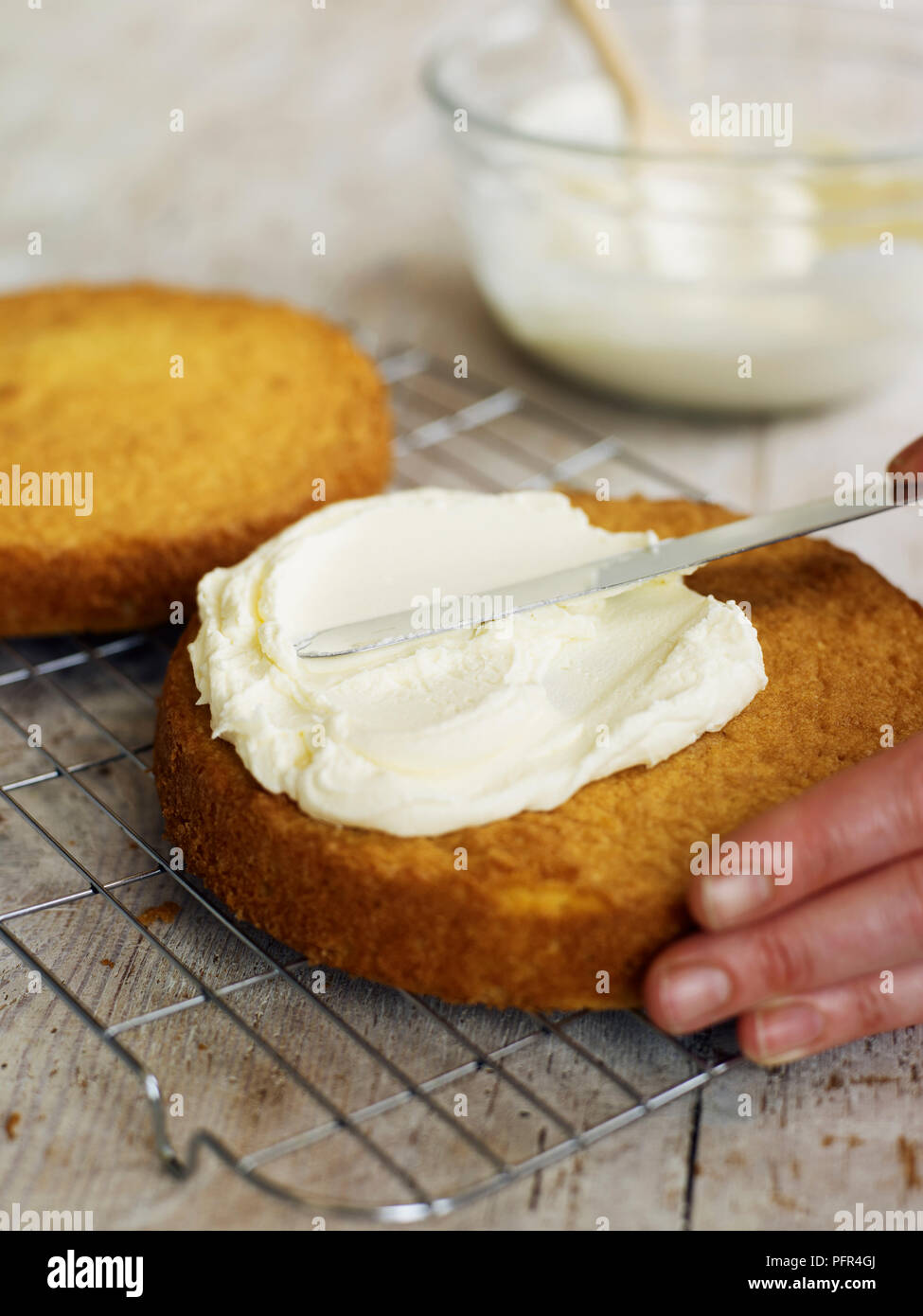 Spreading butter icing on Victoria sponge cake Stock Photo