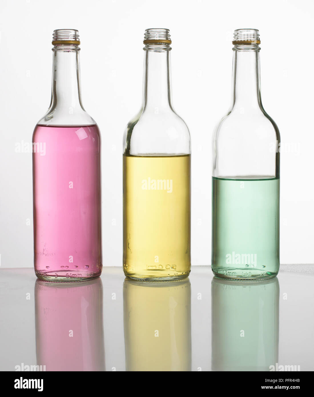 'Bottle pipes' or 'bottle xylophone', three bottles filled with different amounts of coloured water, lined up in a row Stock Photo