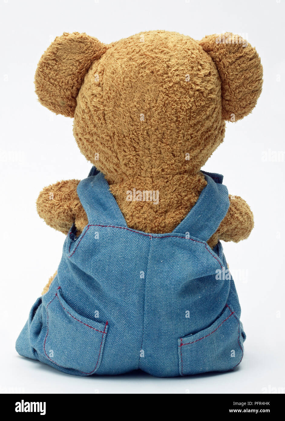 Teddy wearing blue dungarees, rear view Stock Photo