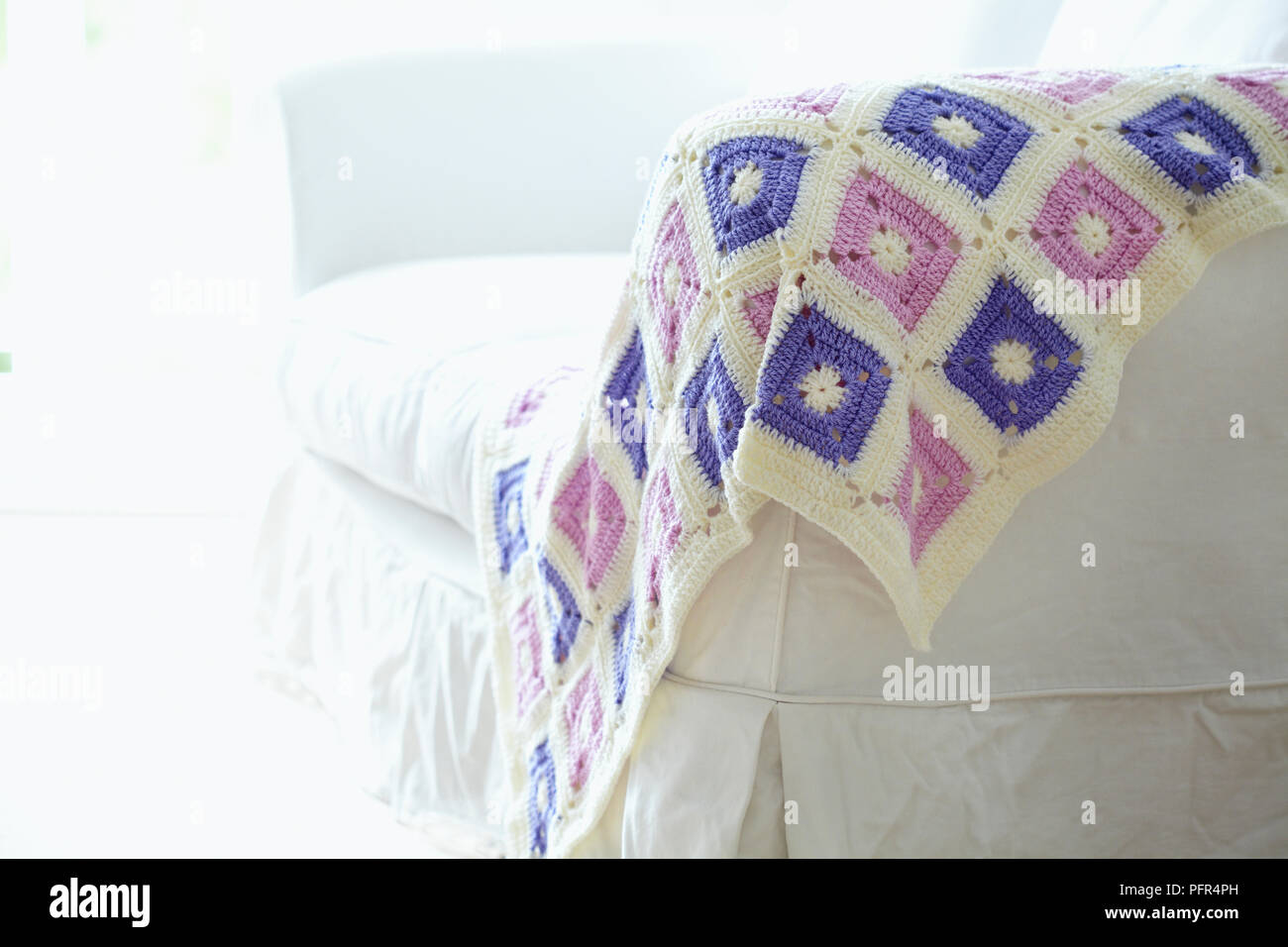 Crocheted patchwork throw on white sofa Stock Photo