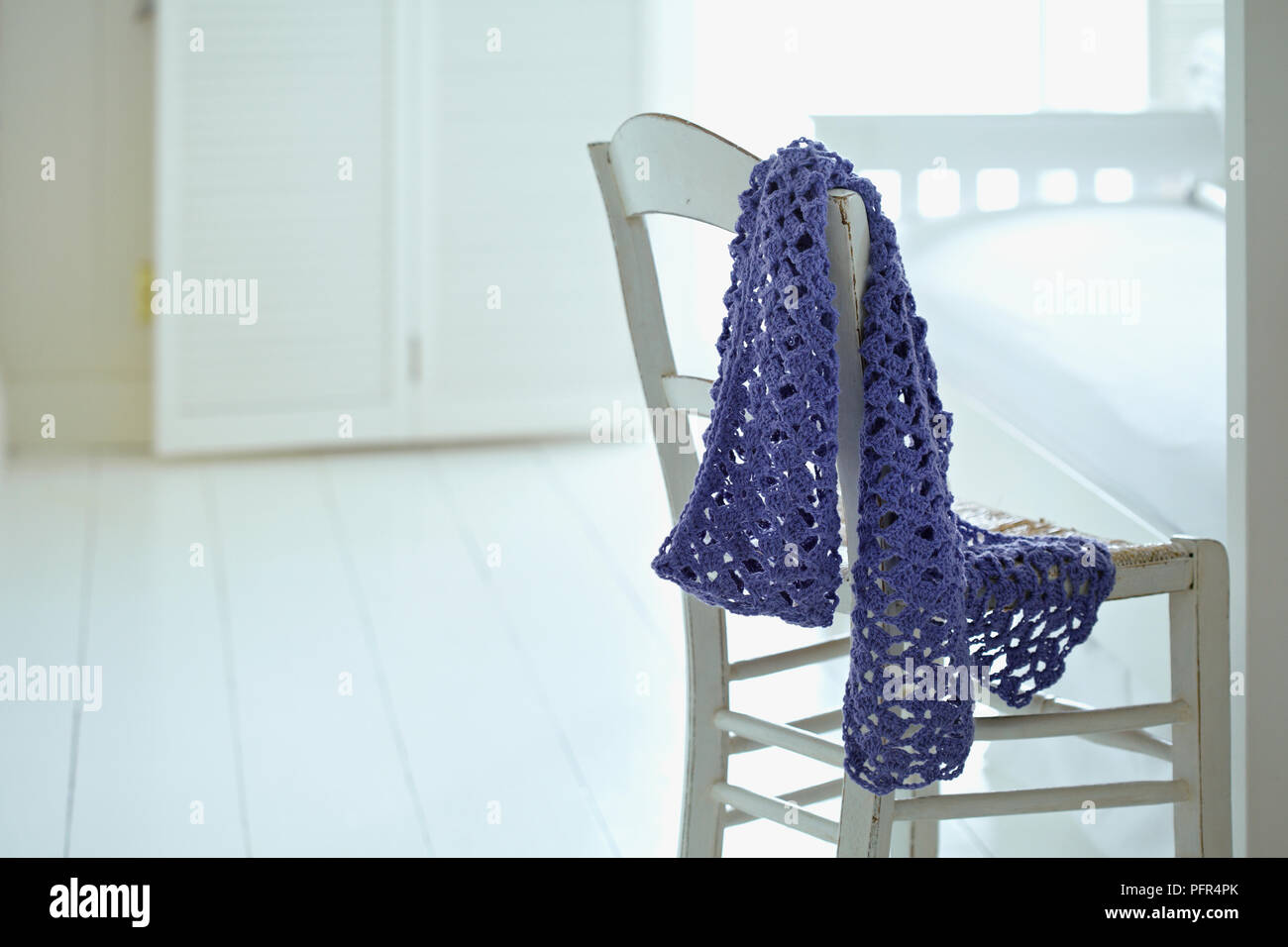 Lacy, purple fans-stitch scarf over back of chair Stock Photo