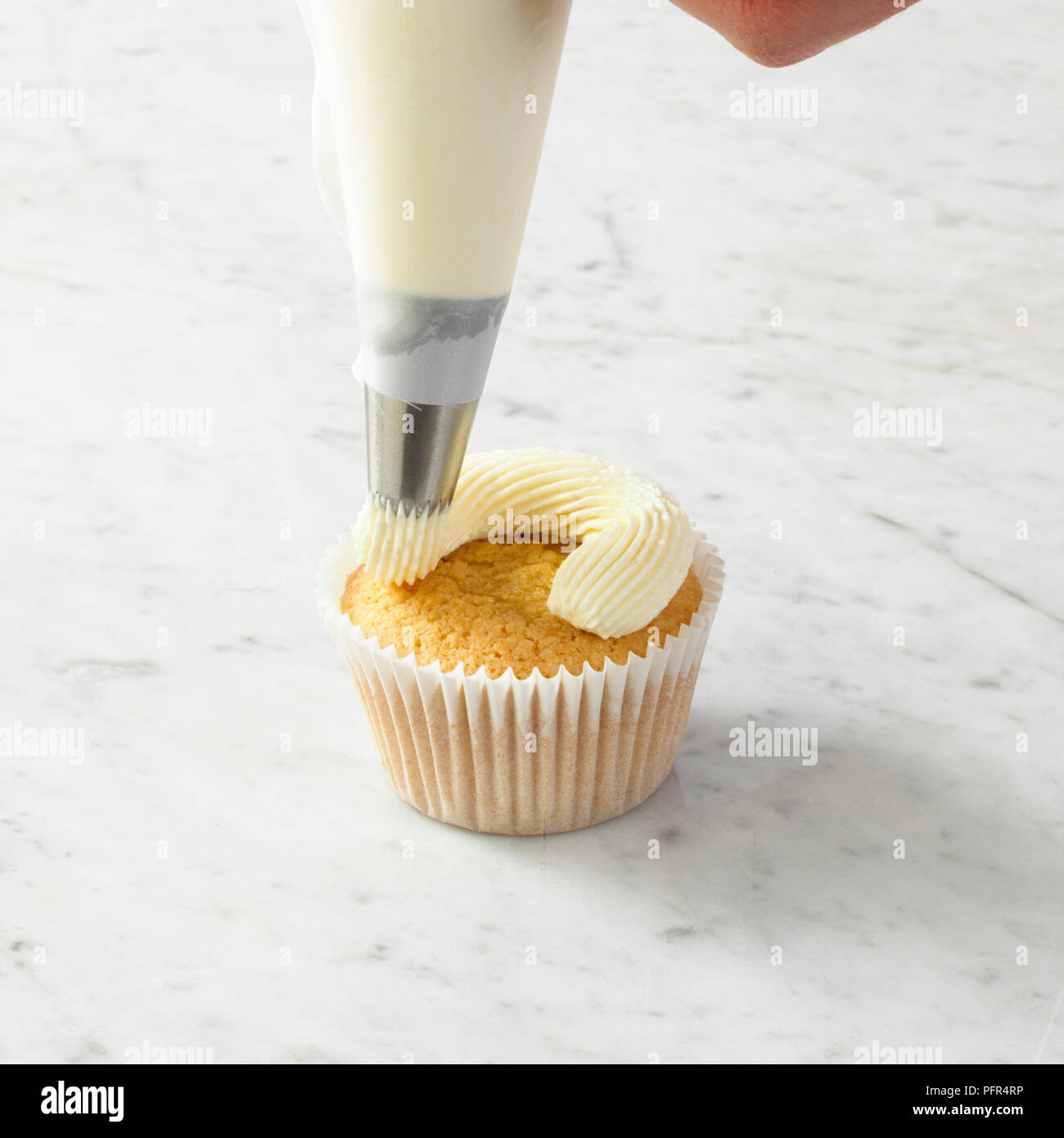 Piping butter icing on top of cupcake Stock Photo