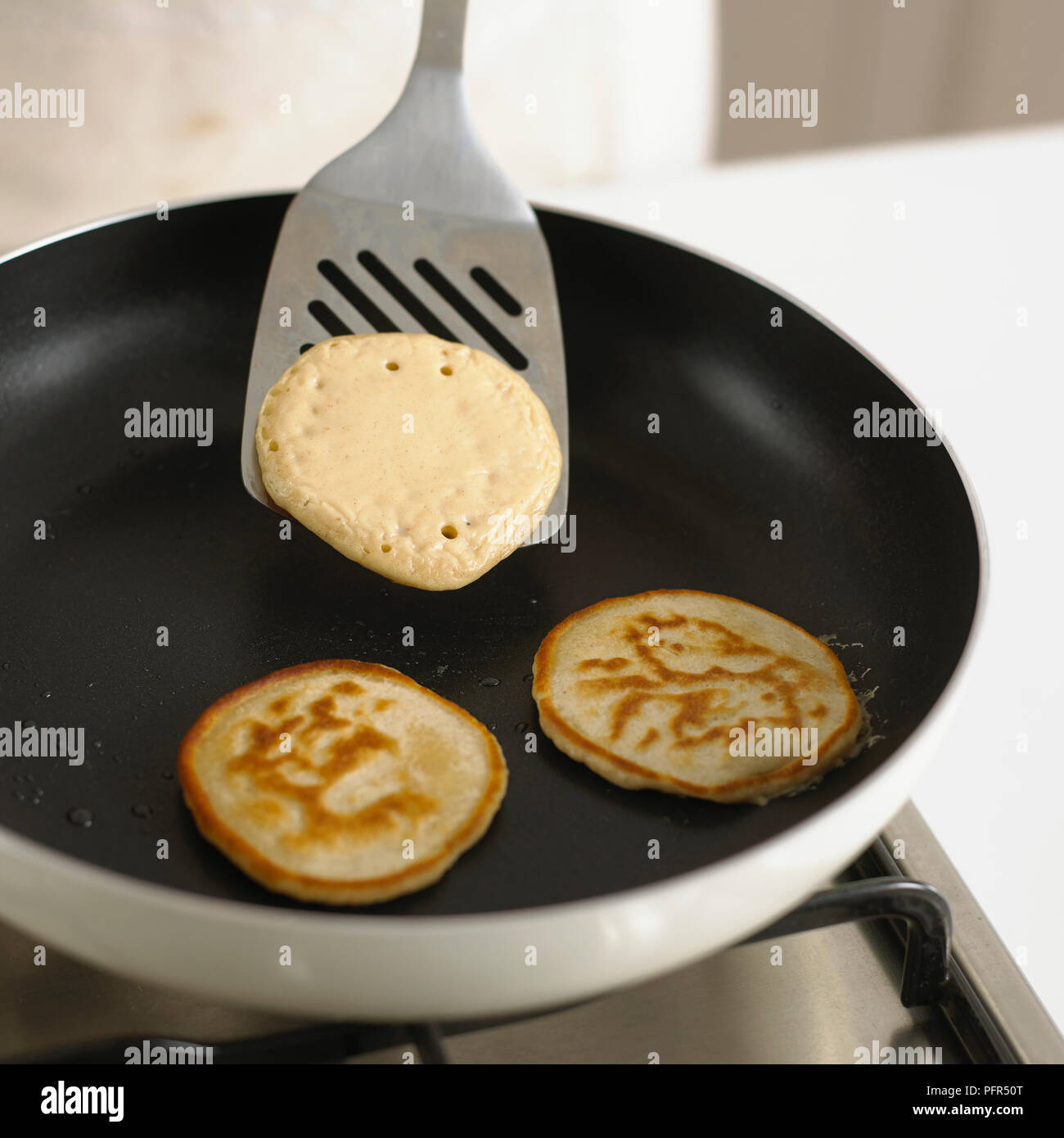 Flipping pancakes in a frying pan Stock Photo
